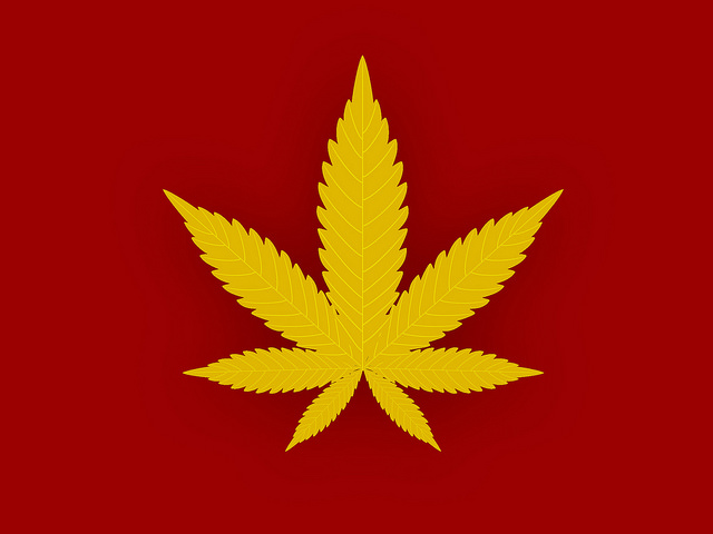 Cannabis flag with gold leaf on red background.