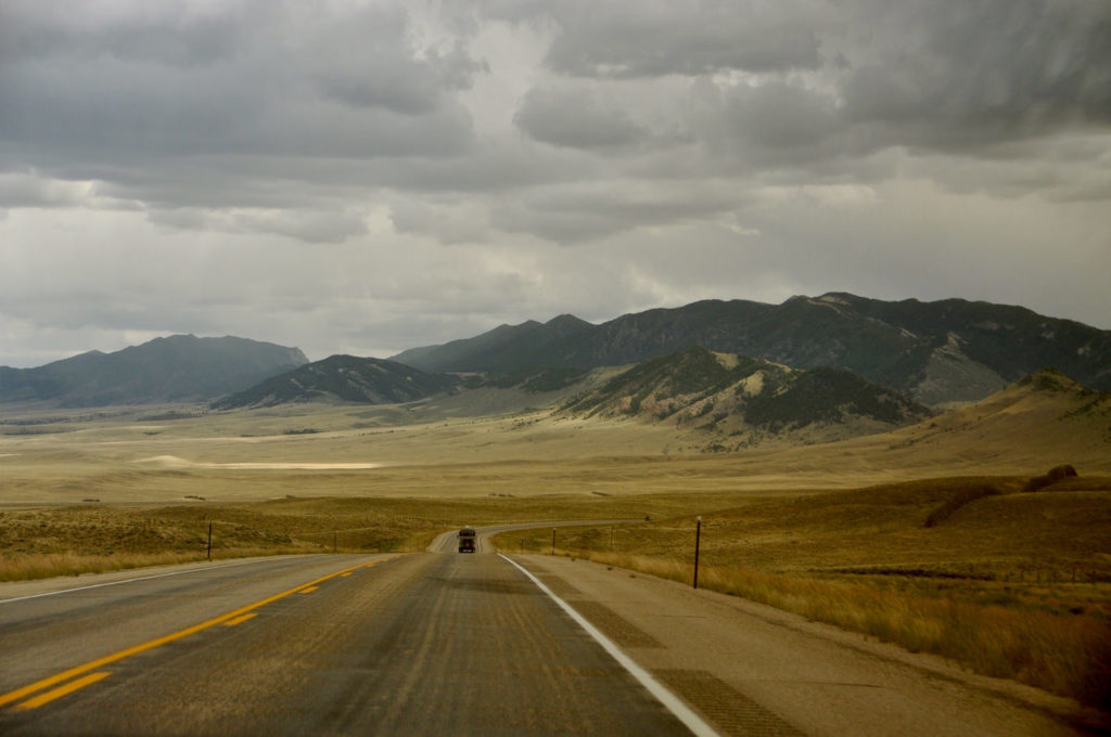 Open road curves across the plains to dramatic highlands.