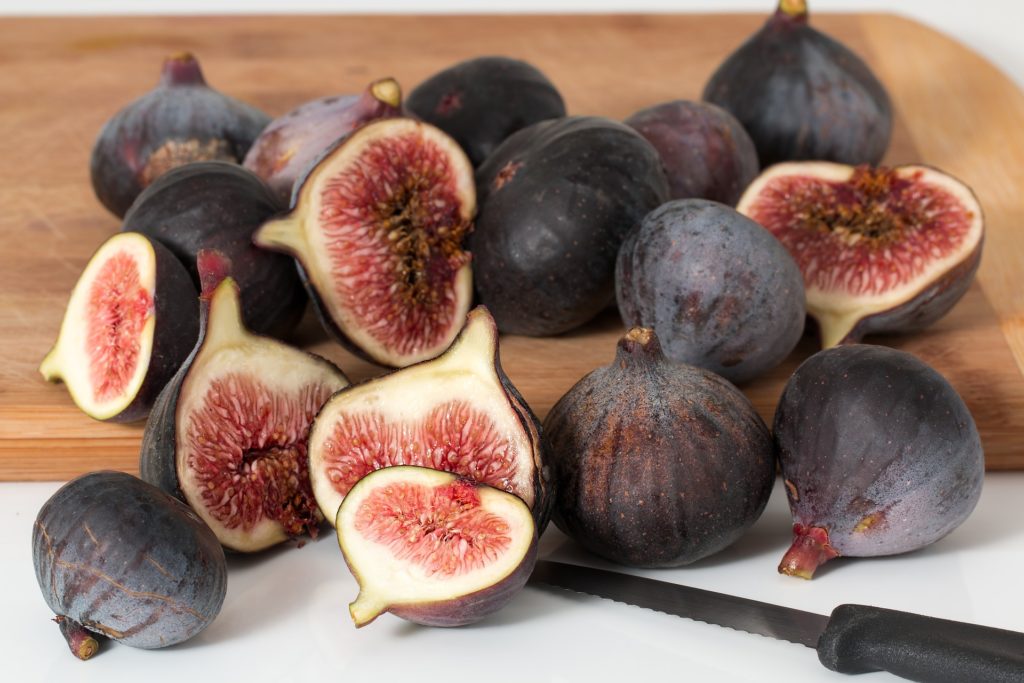 Ripe figs on a chopping board with a knife.